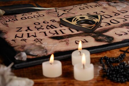 Board with candles. Seance on wooden table. The mystical atmosphere of the call of spirits. Black...