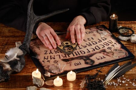 Hands on the devil's board. Session of calling spirits. Occult sciences, the atmosphere of black magic. Occultism.の写真素材