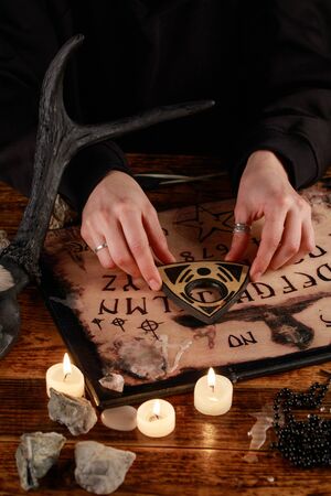 Hands on the devil's board. Session of calling spirits. Occult sciences, the atmosphere of black magic. Occultism.の写真素材