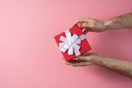 Valentine's Day celebration concept. A nice gift from a loved one. Box with a bow in male hands on a...