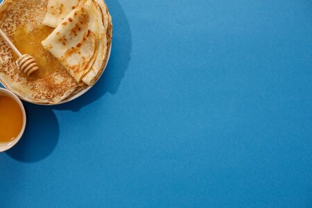 Tasty homemade pancakes with honey on a blue background. Top view, close-up. Traditional holiday...