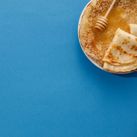 Tasty homemade pancakes with honey on a blue background. Top view, close-up. Traditional holiday...