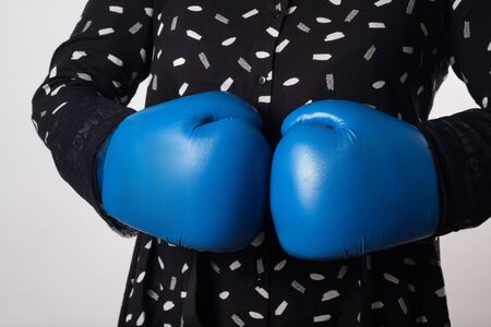 Female power concept. Boxing gloves on a girl in a dress. Close-up.の写真素材
