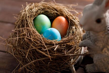 Easter bunny and bird's nest with colored eggs. Easter celebration concept. Close-up.