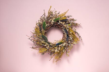 A wreath of dried twigs and flowers on a gently pink background. Natural decoration. Holiday concept. Easter wreath. Willow round frame. Postcard design concept.の写真素材