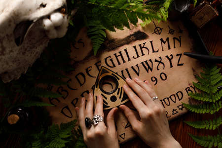 Mystic ritual with Ouija and candles. Devil's board concept, black magic or fortune telling rite with occult and esoteric symbols. Mystical rituals and occult sciences.の写真素材