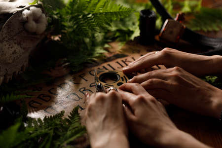 Mystic ritual with Ouija and candles. Devil's board concept, black magic or fortune telling rite with occult and esoteric symbols. Mystical rituals and occult sciences.の写真素材