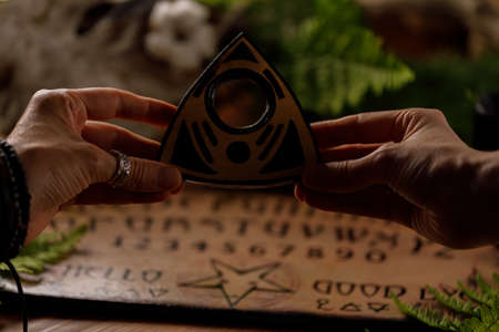 Mystic ritual with Ouija and candles. Devil's board concept, black magic or fortune telling rite with occult and esoteric symbols. Mystical rituals and occult sciences.の写真素材