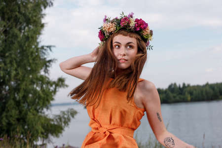 Slavic beauty with a flower wreath on her head in the lap of nature. Ancient pagan origin celebration concept. Summer solstice day. Mid summer.の写真素材