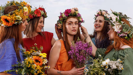 Lovely girls in flower wreaths in nature. Ancient pagan origin celebration concept. Summer solstice day. Mid summer.の写真素材