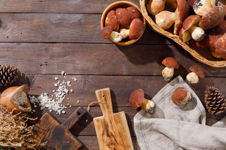 Harvest concept. Wild porcini mushrooms in a handmade wicker basket on a wooden background top view.の写真素材