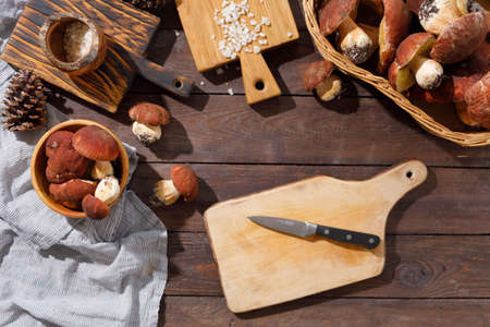 Harvest concept. Wild porcini mushrooms in a handmade wicker basket on a wooden background top view.の写真素材