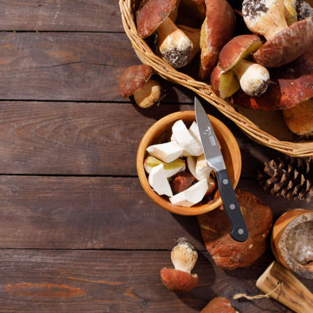 Harvest concept. Wild porcini mushrooms in a handmade wicker basket on a wooden background top view.の写真素材