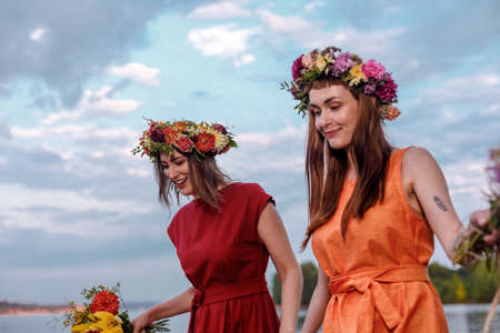 Lovely girls in flower wreaths in nature. Ancient pagan origin celebration concept. Summer solstice day. Mid summer.の写真素材