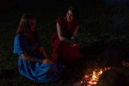 Lovely girls by the fire at night. Ancient pagan origin celebration concept. Night of Ivan Kupala.の写真素材