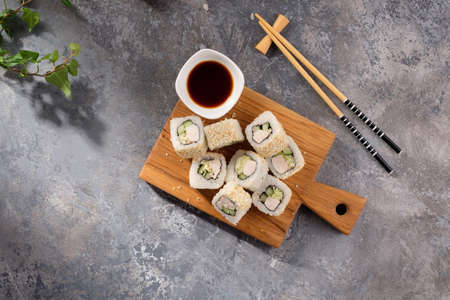 Roll made of Fresh cucumber and chicken and salad inside in a gray background. Delicious food. Beautiful still life with a portion of rolls on a wooden board. Still life.の写真素材