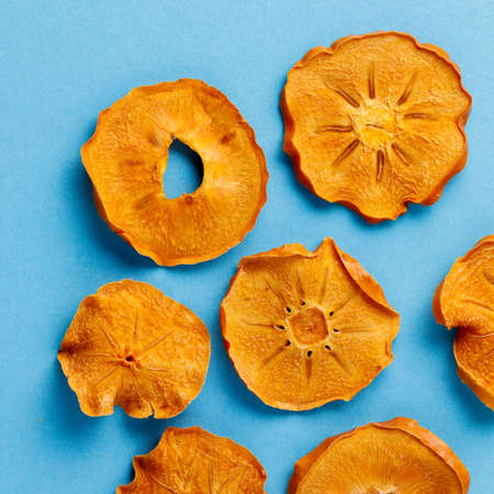 slices of dried persimmon on a blue background. dried fruits. eco. top view.の写真素材
