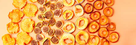 slices of dried persimmon, peach, plum and figs on a orange background. dried fruits. eco. top view.