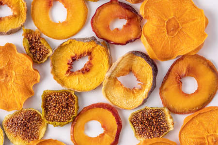 slices of dried persimmon, peach, plum and figs on a white background. dried fruits. eco. delicacy.