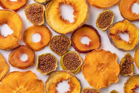 slices of dried persimmon, peach, plum and figs on a white background. dried fruits. eco. delicacy.