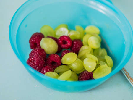 raspberries and grapes in the plastic doseの写真素材