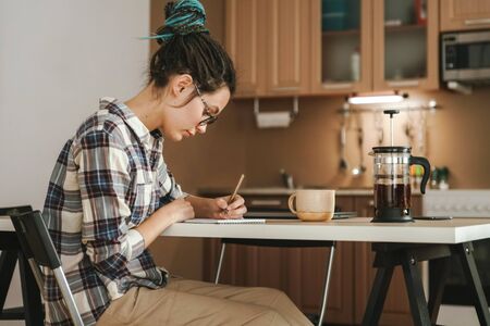 A woman works at home in the kitchen at the dining table. In a relaxed position. Quarantine.