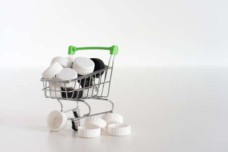 Black and white lids in a small shopping cart on a white background Recycle concept Copy spaceの写真素材