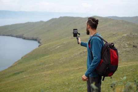 Man with backpack takes picture of the green bank on his phone Travel photography Copy space Wild natureの写真素材