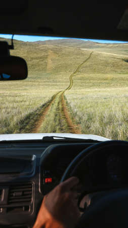 Vertical view from car window Off road trip in the fields Passengers hand on the steering wheel Long...