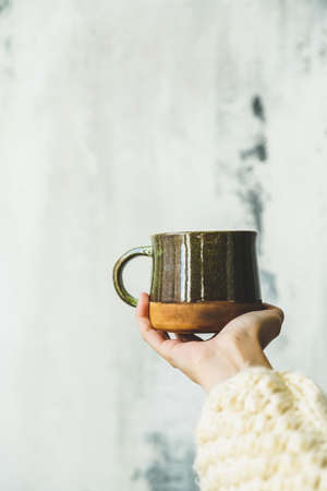 Hand in sweater holding cup