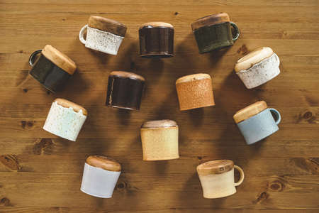 Top view of ceramic cups. Handmade cups with and without handles. Wooden background