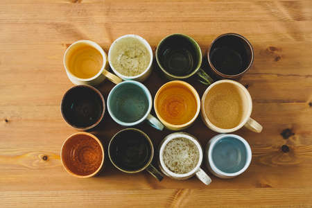 Top view of colorful handmade ceramic cups on a wooden table
