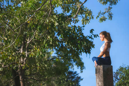 Athletic girl warming up in the park. Warming up before runing. Morning sun.