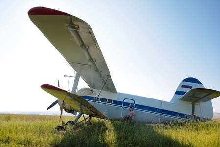 Propeller aircraft in the green field and posing girl. Warm summer photo. Clear blue sky. Freedom...