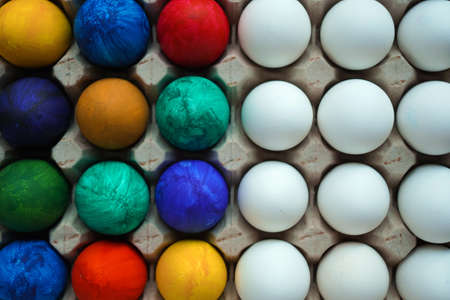 Half colored and half white eggs in square cardboard stand. Easter concept, copy space Top viewの写真素材