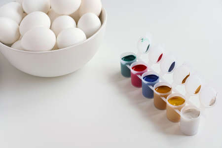 White bowl of eggs and colorful paints on white background. Easter concept. Copy spaceの写真素材