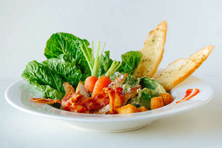 Fancy cooked chicken meat with fried bacon on lettuce leaves with whole carrots, toasted white bread. Fancy restaurant dishの写真素材