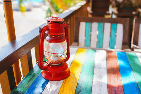 Red old fashioned lamp on colorful wooden table. Bright warm sun, vacation conceptの写真素材