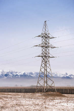 Provision of electricity concept. Power line in fields on background of snowy mountainsの写真素材