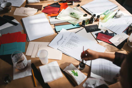 Creative mess on the table of an artist who practices writing with fountain pen. Calligraphy lesson on a messy table in a sunny classroom.の写真素材