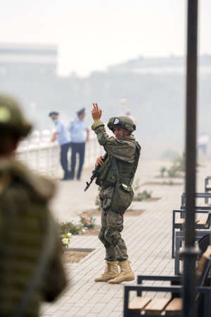 Kaspiysk, Dagestan, Russia - July 25, 2021: Soldier in military uniform with gun shows hand gesture to the rest of soldiers. Military operations in peacetime. Military exercises or war games.のeditorial素材