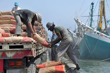 Indonesian port workers unload a ship with a cement bags cargo in a traditional way in Sunda Kelapa port on March 22 in Jakarta 2015, Indonesia.のeditorial素材