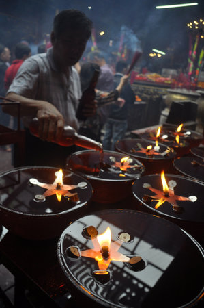 Old man was spilling oil into the container for prayer in the templeのeditorial素材