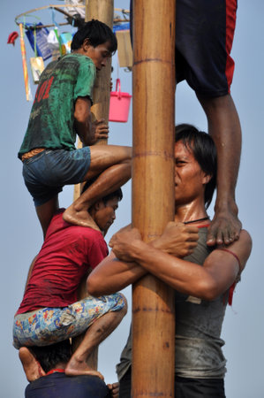 Jakarta, Indonesia - August 17, 2014: Indonesian men in teams try to climb to the top of a greased pole called a panjat pinang in order to get to the prizes tied to the topのeditorial素材