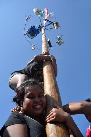 Jakarta, Indonesia-August 17, 2013: Indonesian woman in teams try to climb to the top of a greased...