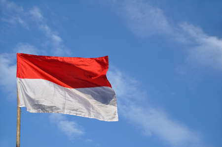 Indonesia's red and white flag flying against blue sky backgroundの写真素材