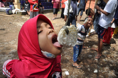 Ciamis, Indonesia - August 17, 2021: Children taking part in a cracker eating competition on the celebration of the independence day of the Republic of Indonesia, Ciamis, West Java-Indonesiaのeditorial素材