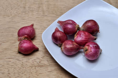 Onions on a white plate on a wooden table in the kitchen