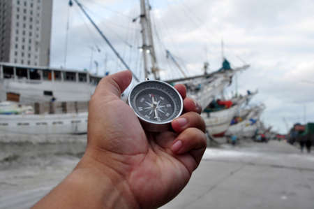 Holding a navigation compass with a harbor atmosphere backgroundの写真素材