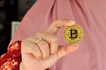 Close up of asian woman holding bitcoin with her right handの写真素材